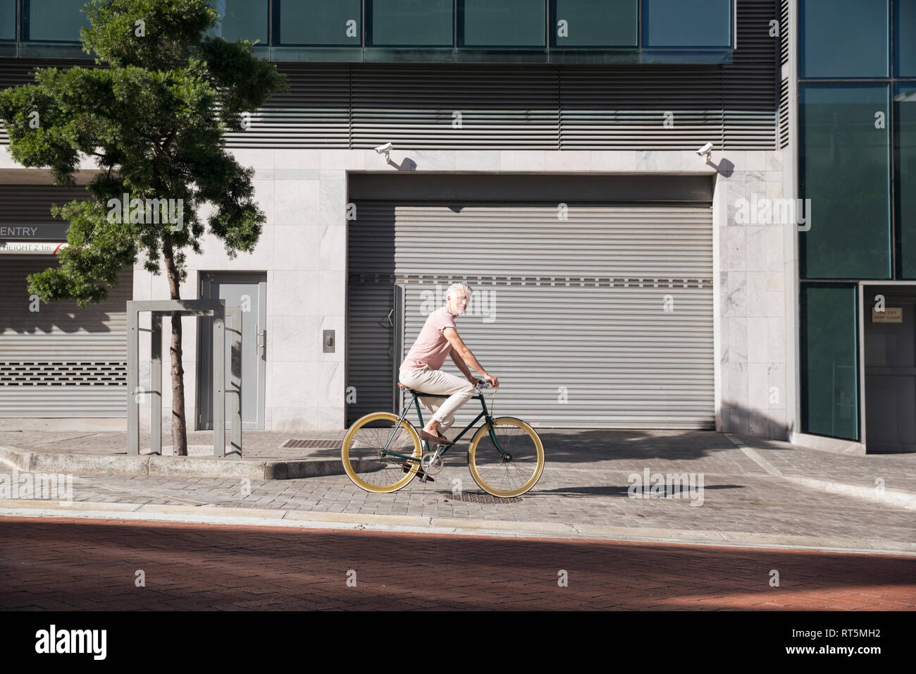 Uomo maturo in sella in bicicletta in città Foto Stock