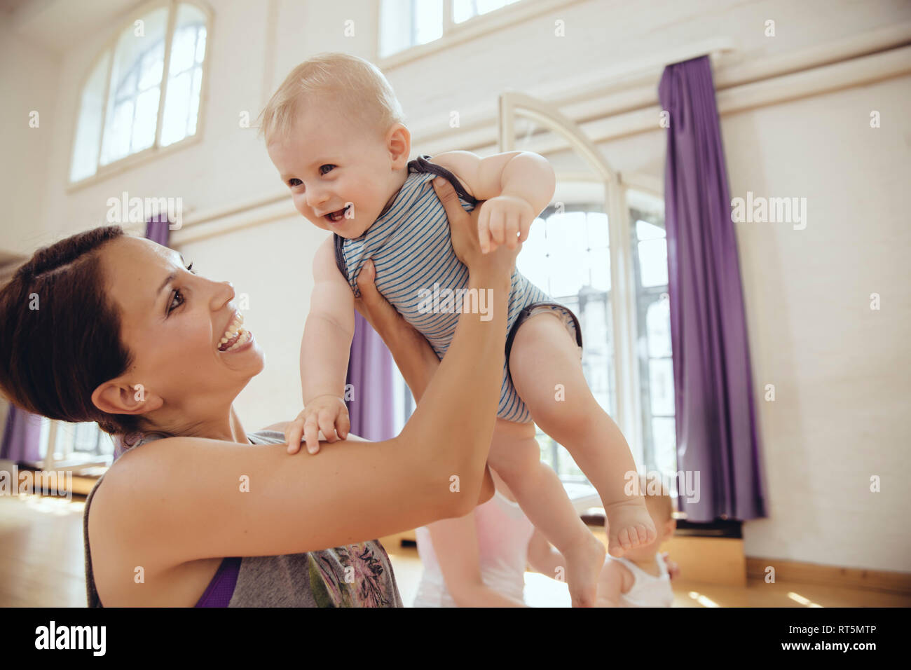 Felice madre sollevando il suo bambino in una sala esercizi Foto Stock