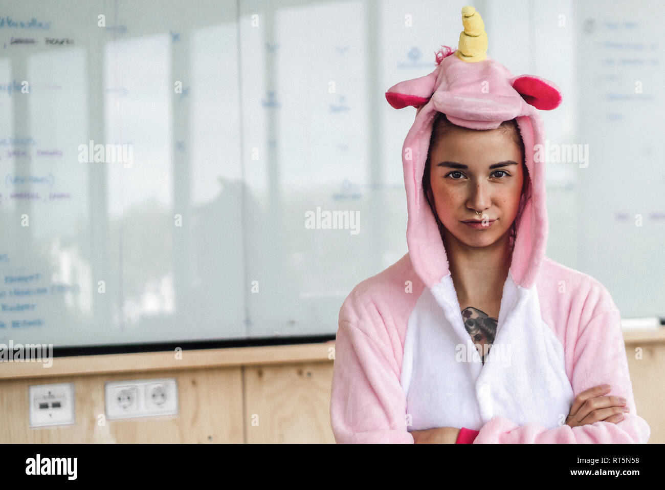 Donna che indossa unicorn onesie, in piedi di fronte a whiteboard, cercando testardo Foto Stock