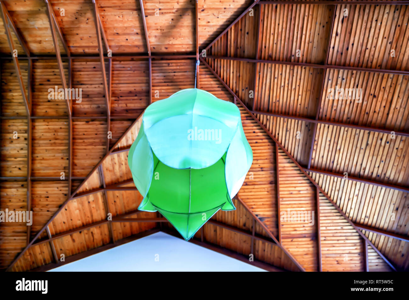 Un paralume verde/lampadario/apparecchio di illuminazione sospeso da un altissimo soffitto in legno. Foto Stock