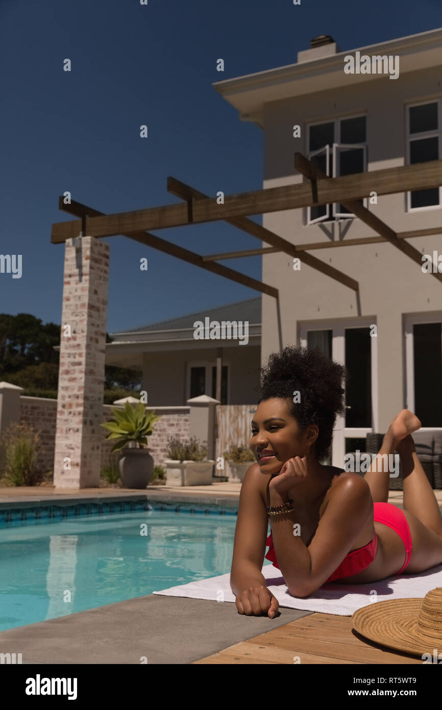 Donna rilassarsi vicino alla piscina in una giornata di sole Foto Stock