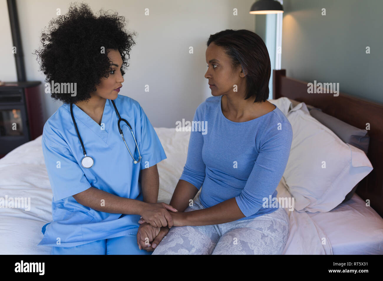 Medico donna consolante senior donna in camera da letto Foto Stock