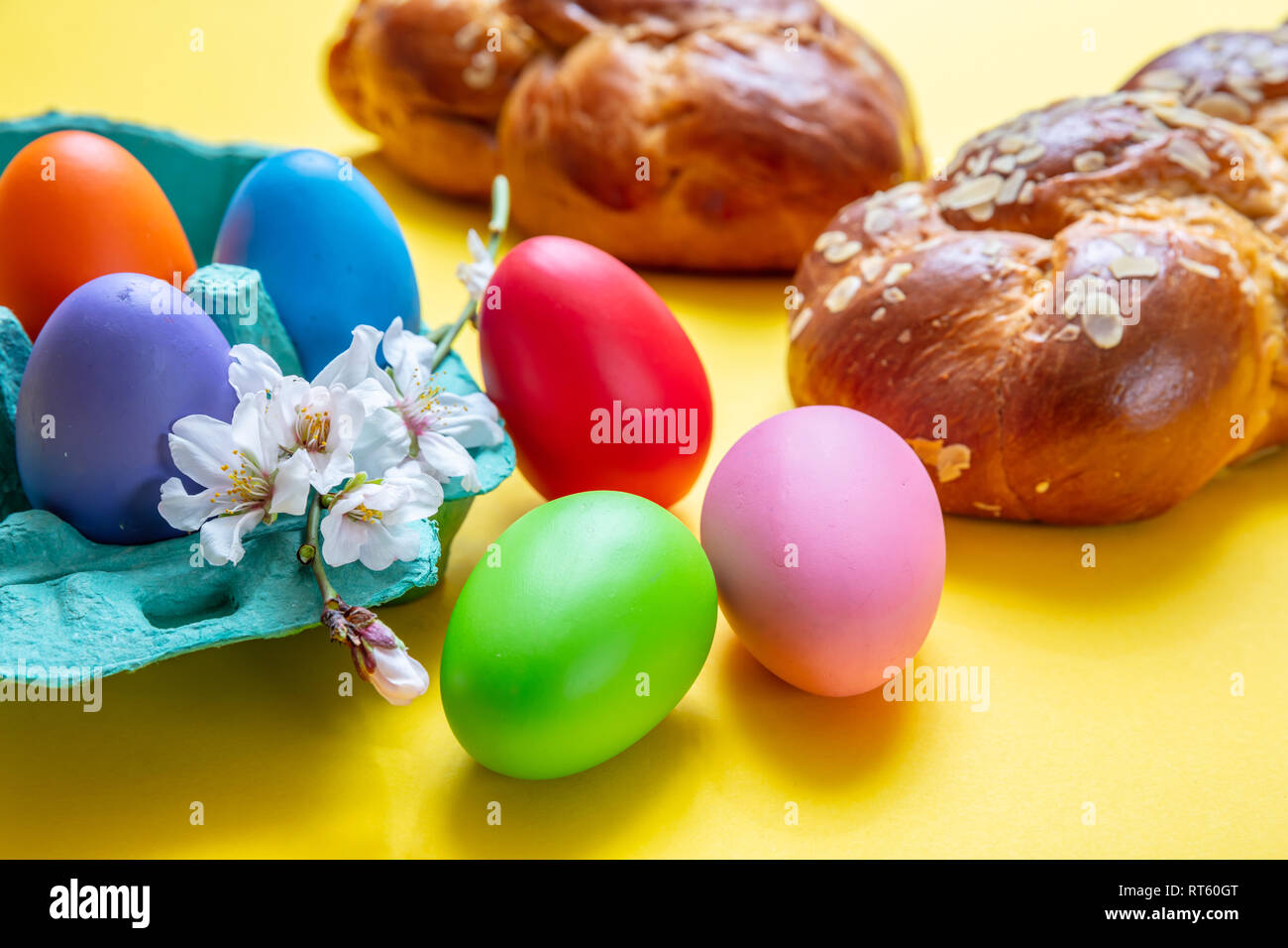 Uova di Pasqua e tsoureki treccia, la Pasqua greca pane dolce, su giallo colore di sfondo Foto Stock