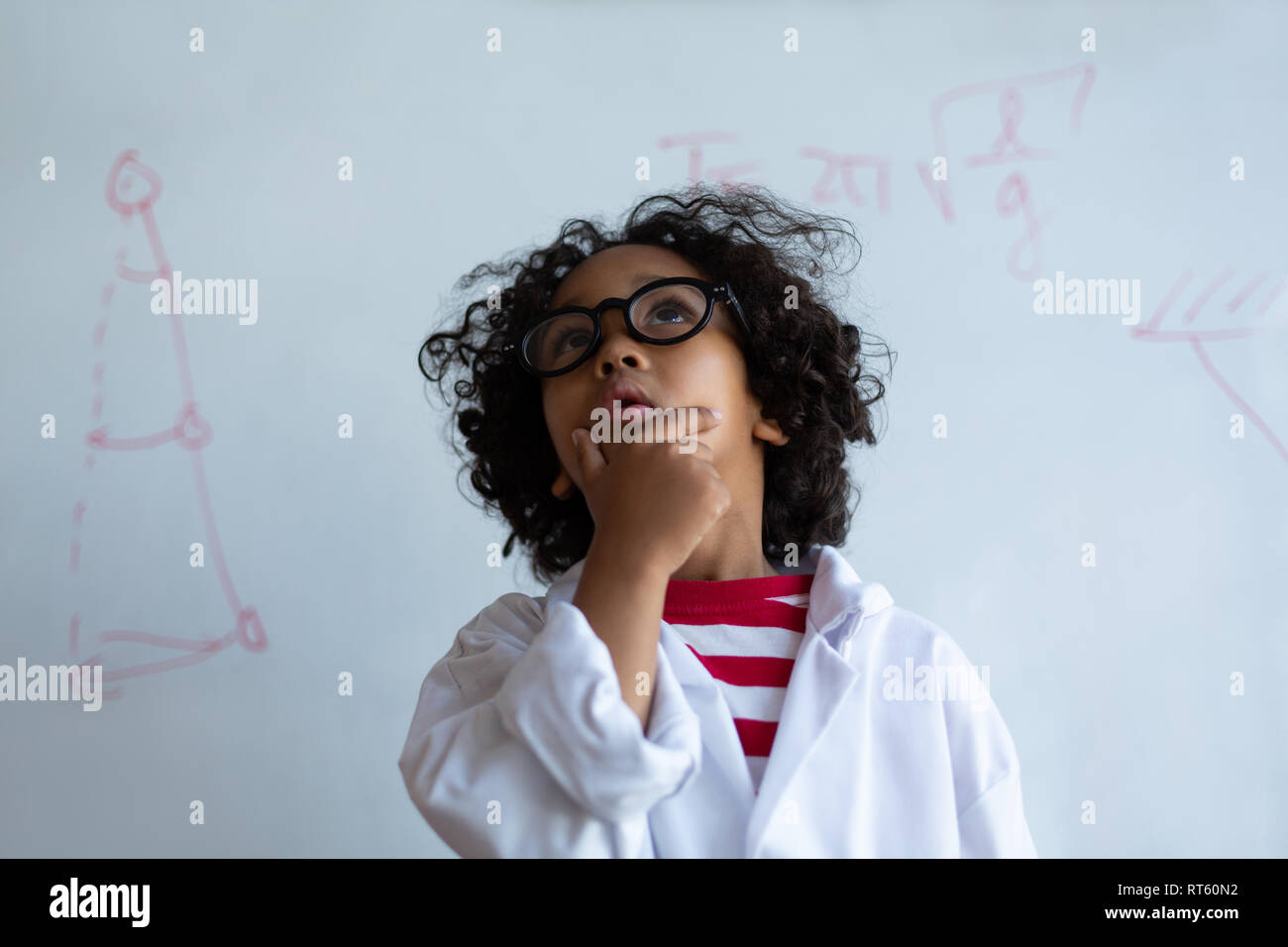 Mixed-gara Schoolboy in chimica rivestire in piedi in laboratorio Foto Stock
