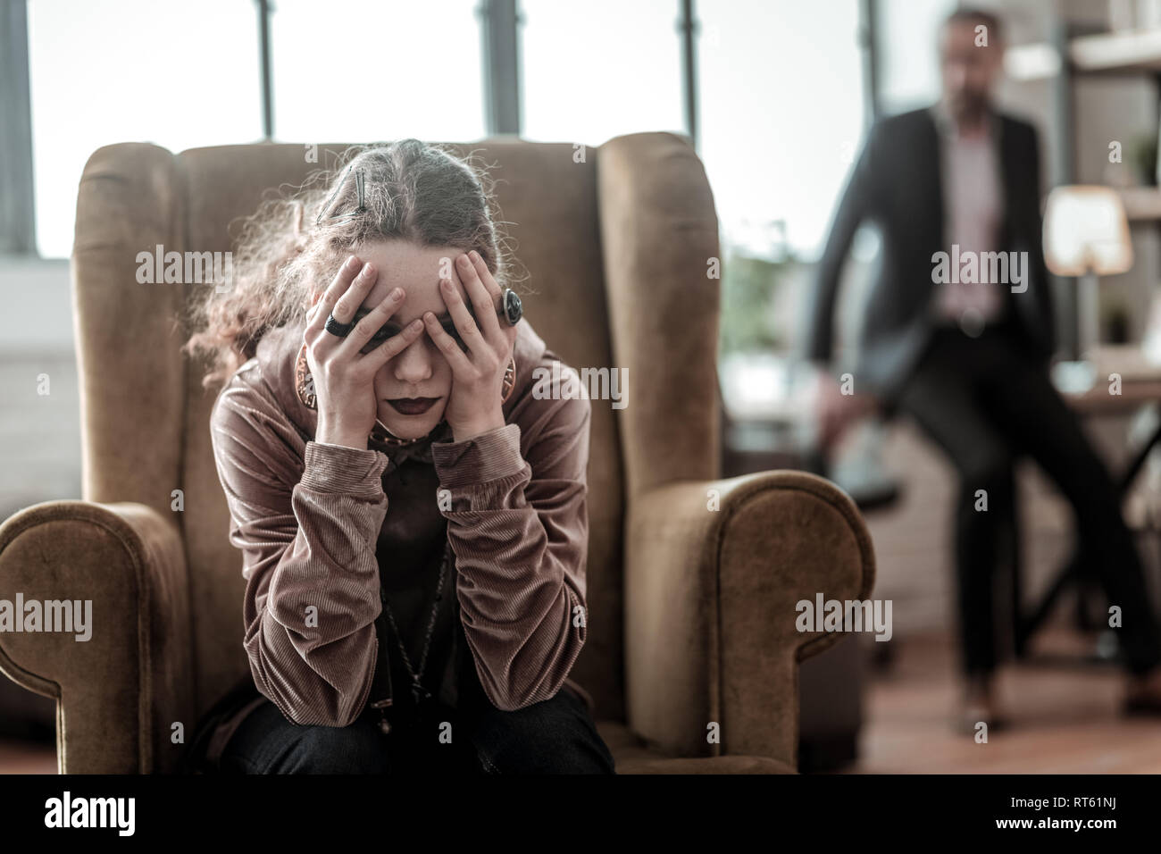 Testina di afferraggio. Curly ragazza adolescente afferra per la testa dopo litigare con suo padre a casa Foto Stock