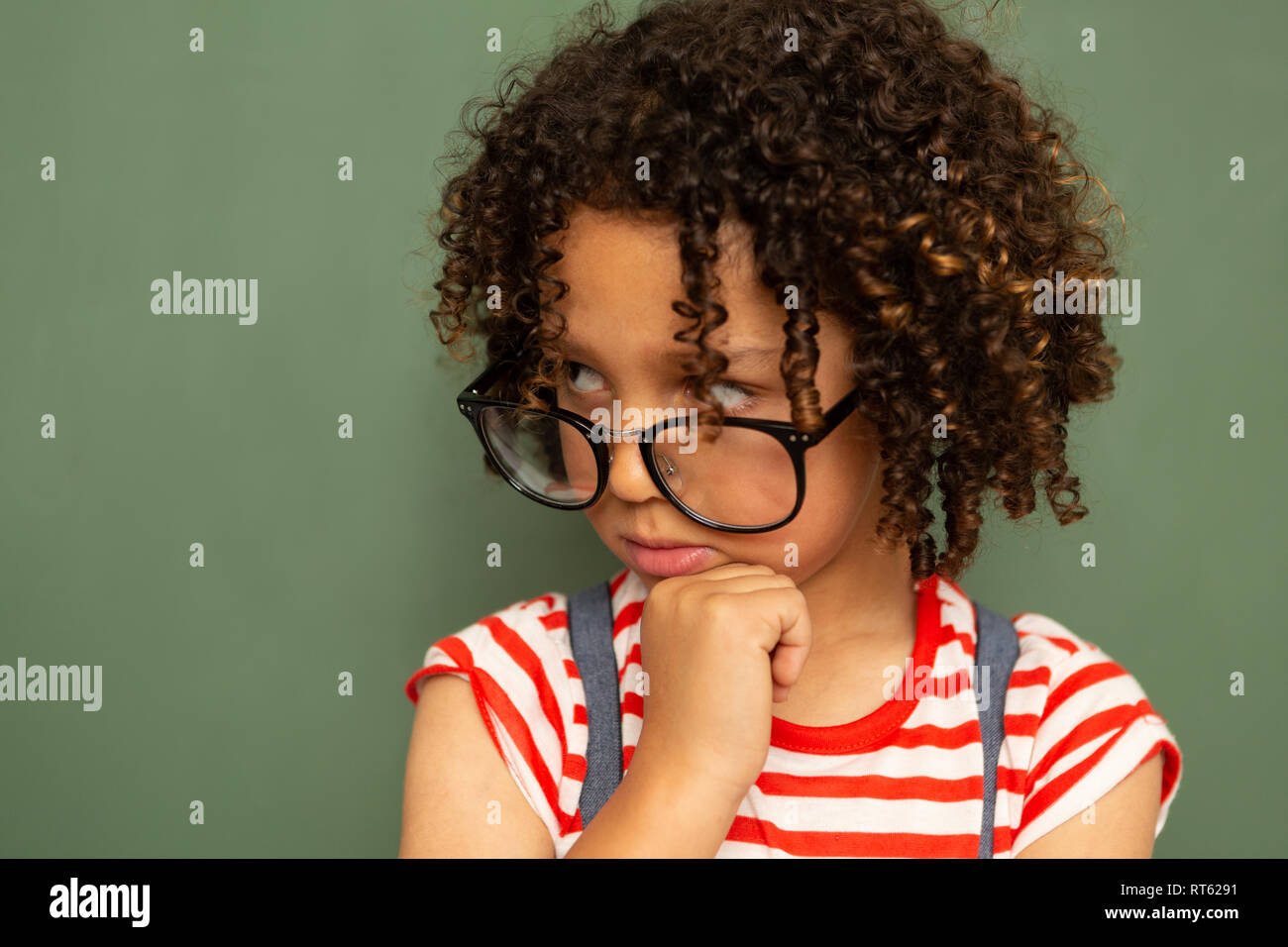 Schoolgirl in piedi contro la scheda verde in una classe a scuola Foto Stock