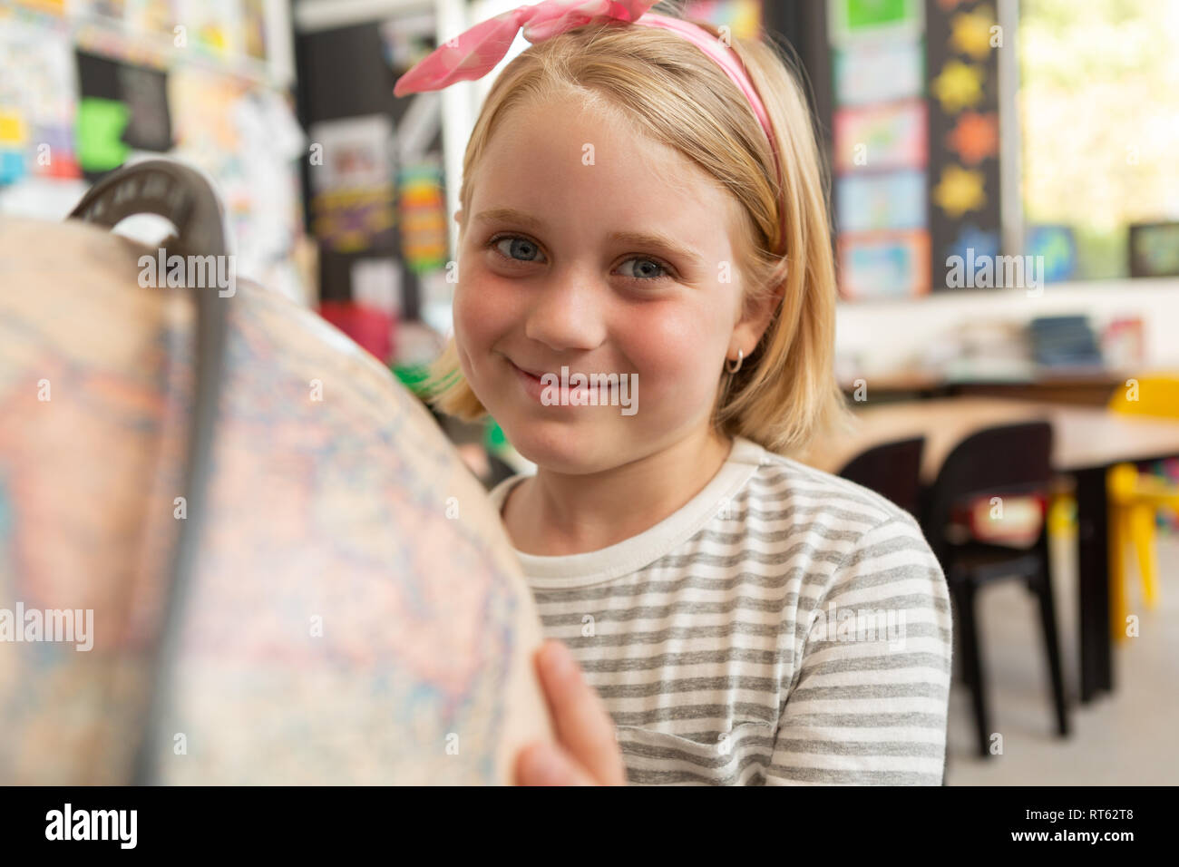 La scolaretta globo di studiare in una classe Foto Stock