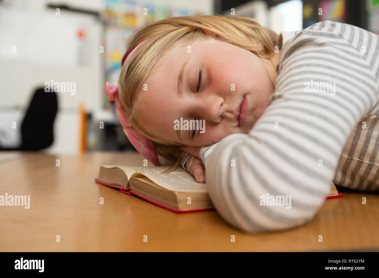 Schoolgirl dormire su di prenotare alla reception in aula Foto Stock