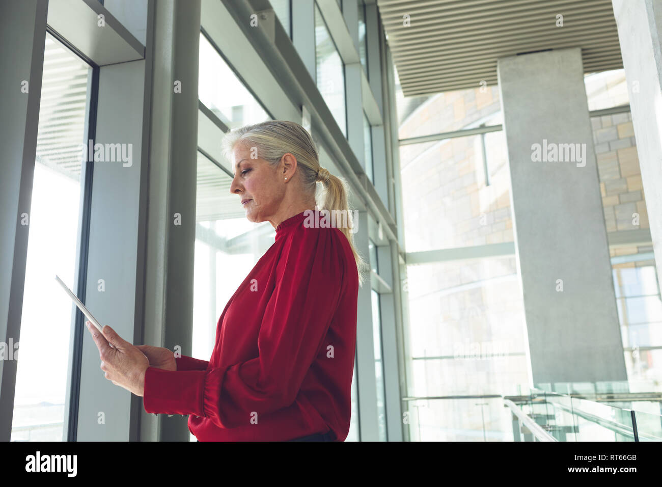 Senior imprenditrice utilizzando digitale compressa in edificio per uffici Foto Stock
