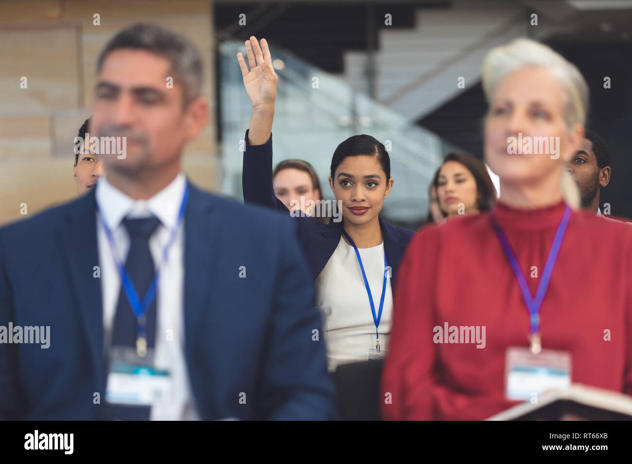 Giovane imprenditrice alzando la mano in un seminario di business Foto Stock