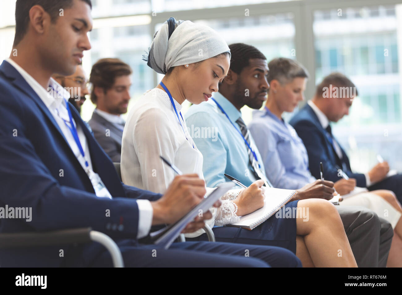 La gente di affari la scrittura su notepad durante il seminario Foto Stock