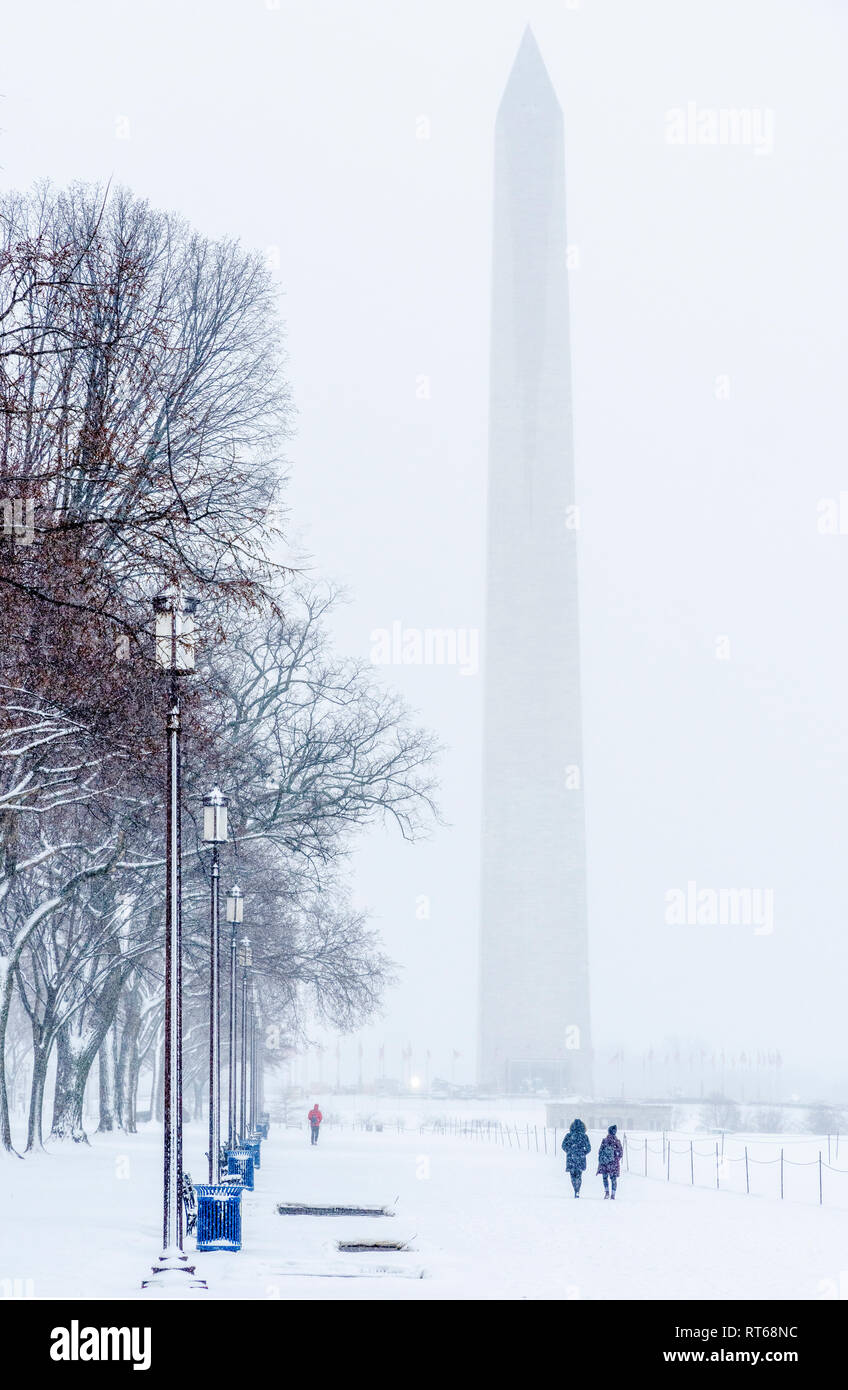 Il Monumento a Washington in un giorno di neve a Washington DC, con alberi di Olmo, lampioni, e visitatori. Foto Stock