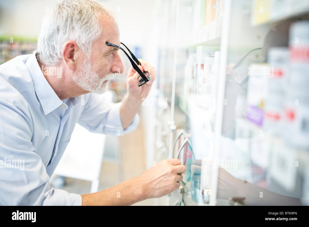 Uomo maturo guardando armadio con medicine in farmacia Foto Stock
