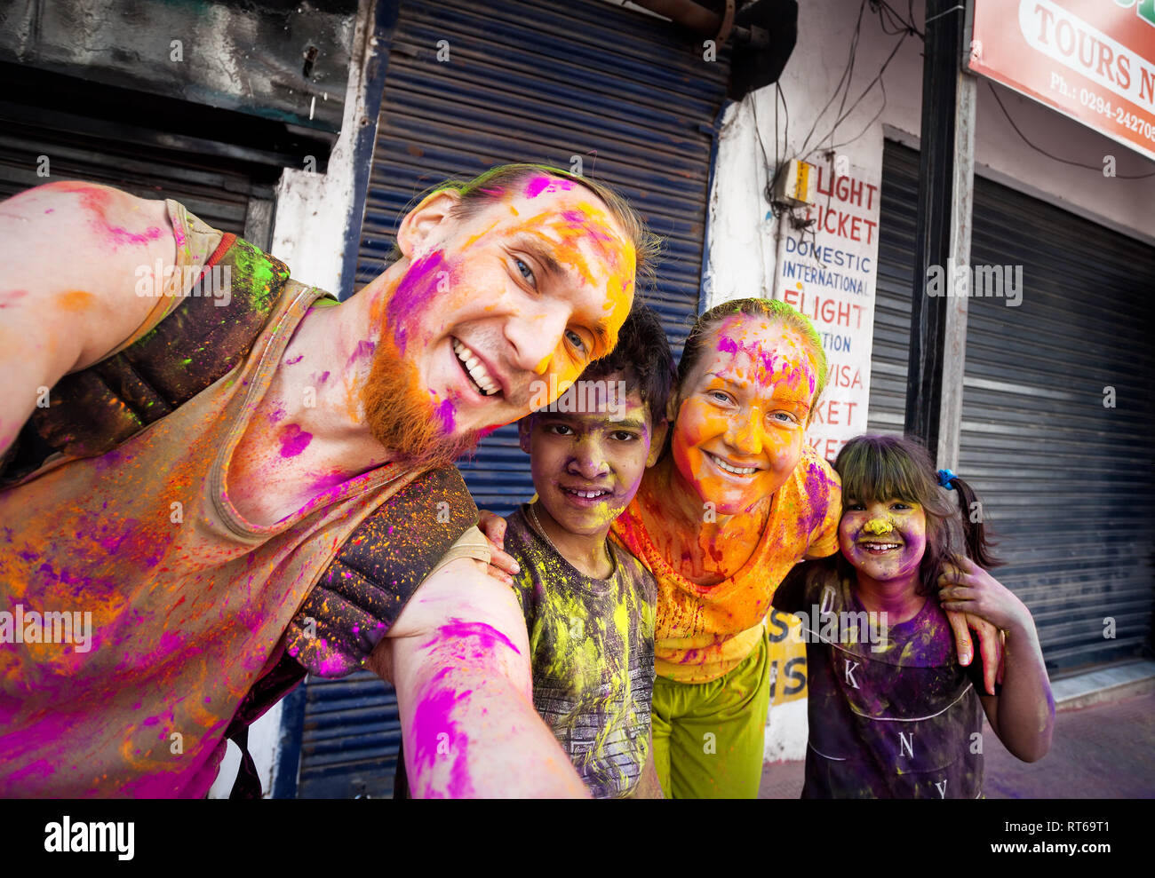 Udaipur, India - 6 Marzo 2015: Selfie foto di bambini Indiani e coppia estera con faccia dipinta celebrando il coloratissimo festival di Holi sul Foto Stock