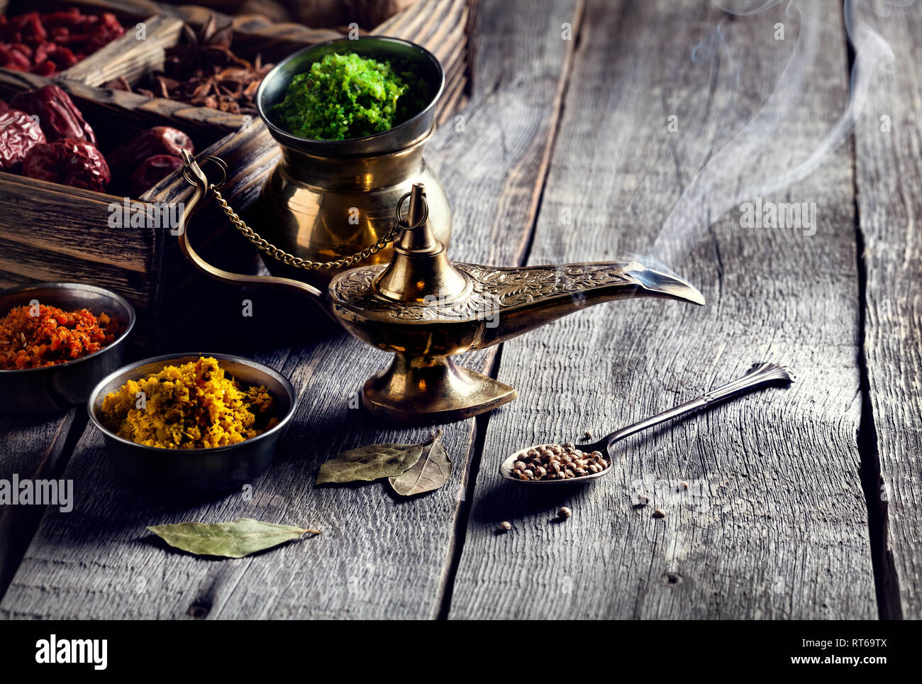 Lampada Aladdin dal bronzo e asciugare le spezie a sfondo di legno con cucchiai nelle vicinanze Foto Stock
