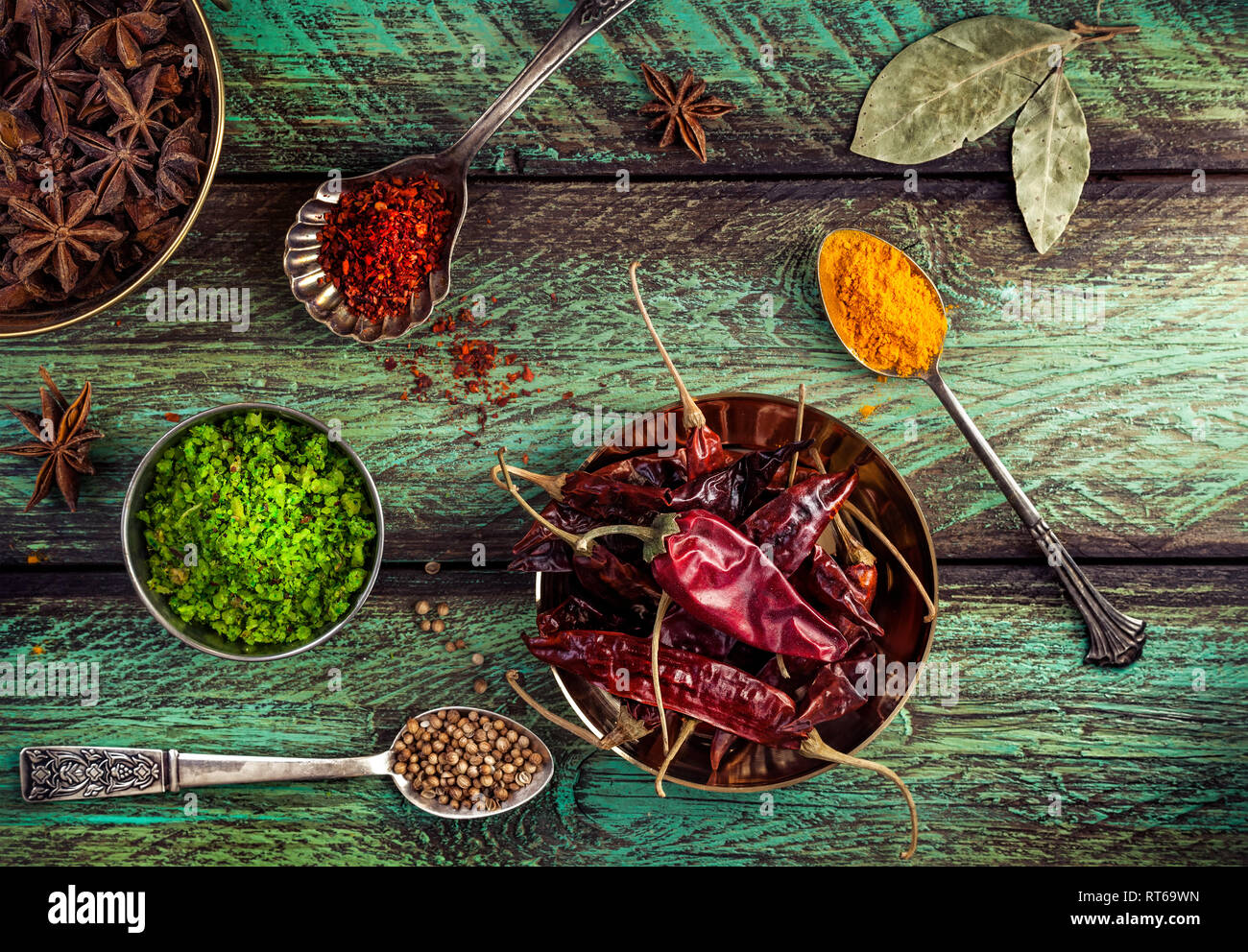 Spezie, secco peperoncino rosso in legno sfondo verde con cucchiai nelle vicinanze Foto Stock