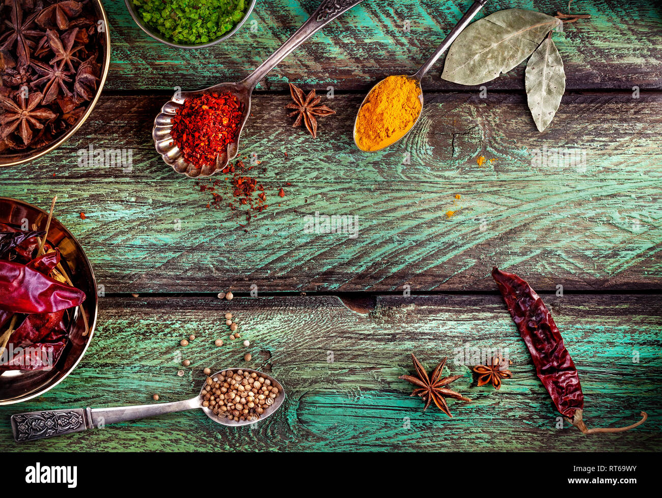 Spezie, secco peperoncino rosso in legno sfondo verde con cucchiai nelle vicinanze Foto Stock