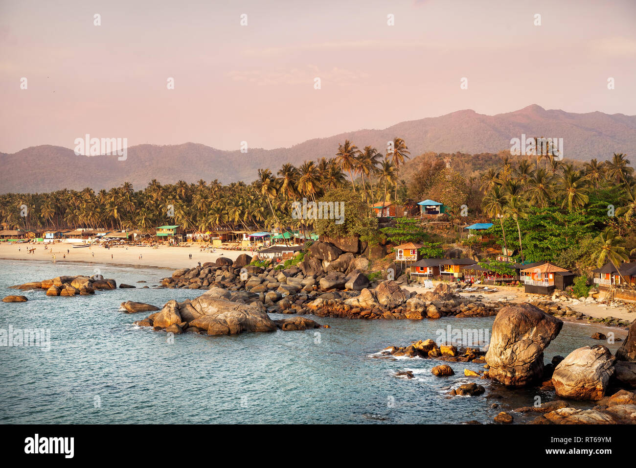 Bellissima vista del tramonto tropicale spiaggia con bungalow e palme di cocco a Palolem in Goa, India Foto Stock