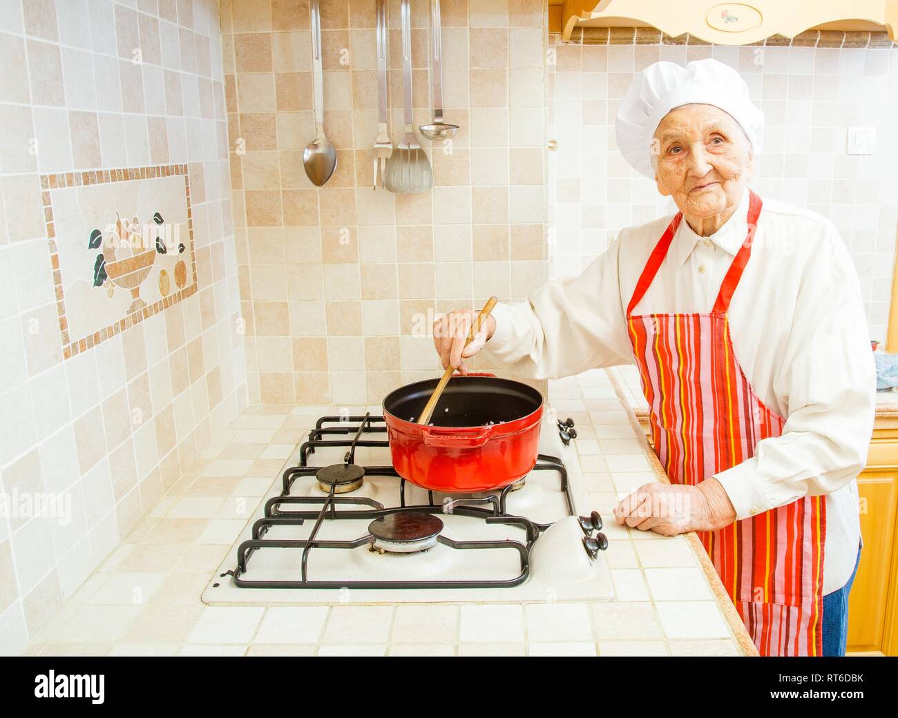 Signora anziana in cucina cucinare la cena. Foto Stock