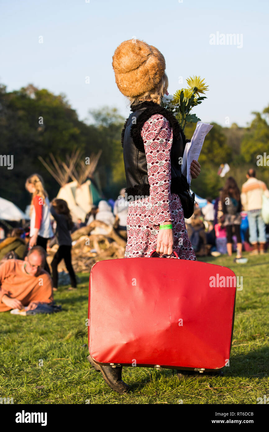 Lady arriva al Beltane Fire Festival con grande valigia rossa e mazzo di fiori, Sussex, Regno Unito Foto Stock