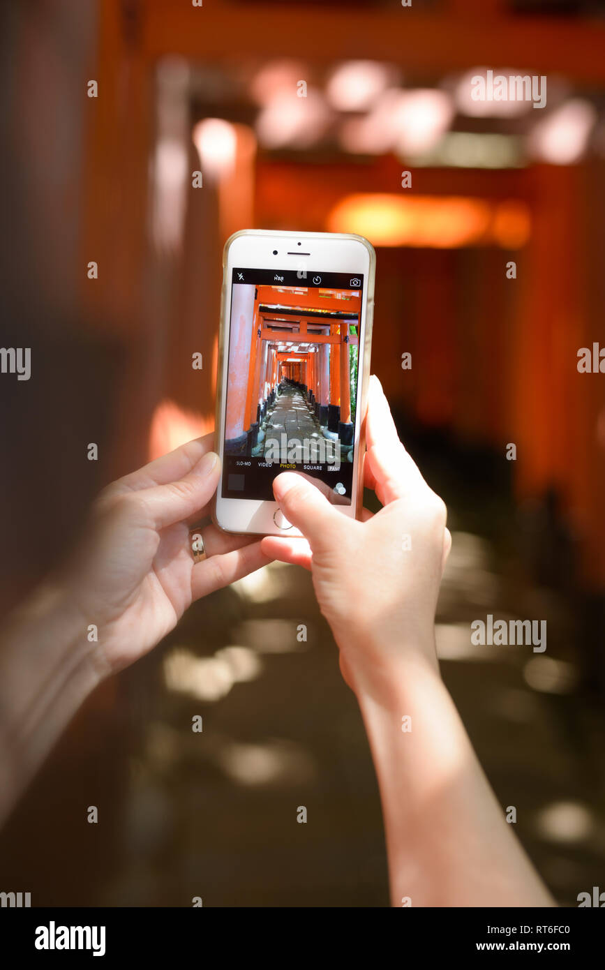 La donna utilizza smart phone per fotografare i cancelli Torii di Sacrario scintoista Fushimi Inari taisha a Kyoto, Giappone. Fushimi Inari taisha-sul Monte Inari è la testa Foto Stock