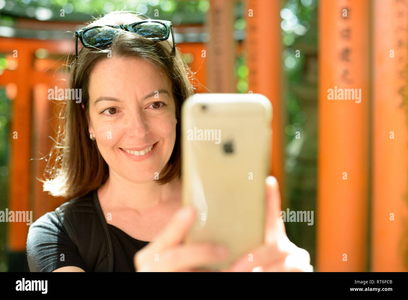 La donna utilizza smart phone per fotografare i cancelli Torii di Sacrario scintoista Fushimi Inari taisha a Kyoto, Giappone. Fushimi Inari taisha-sul Monte Inari è la testa Foto Stock