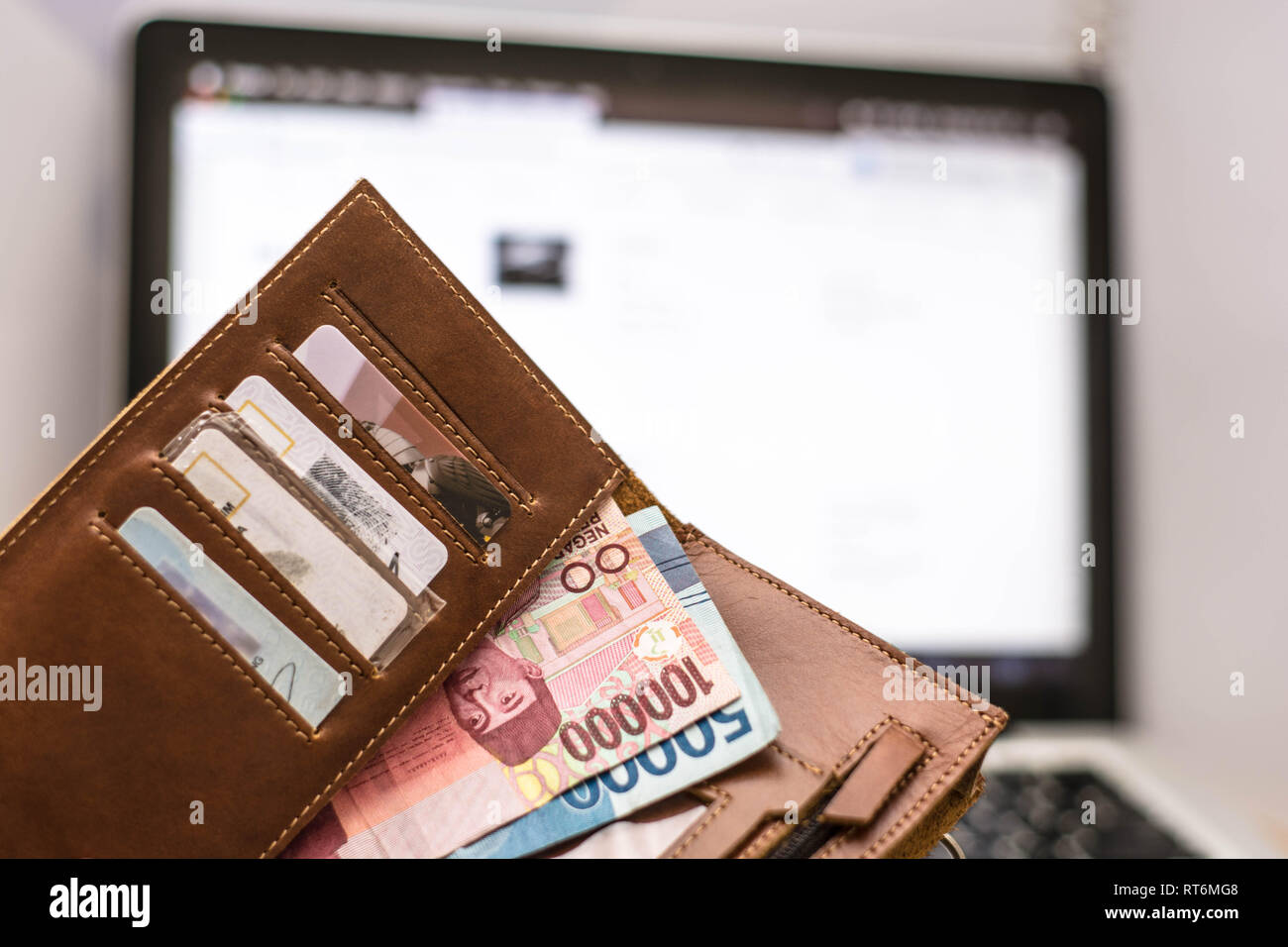 Portafoglio con denaro rupiah internamente nella parte anteriore del computer portatile schermo monitor, online il concetto di transazione Foto Stock