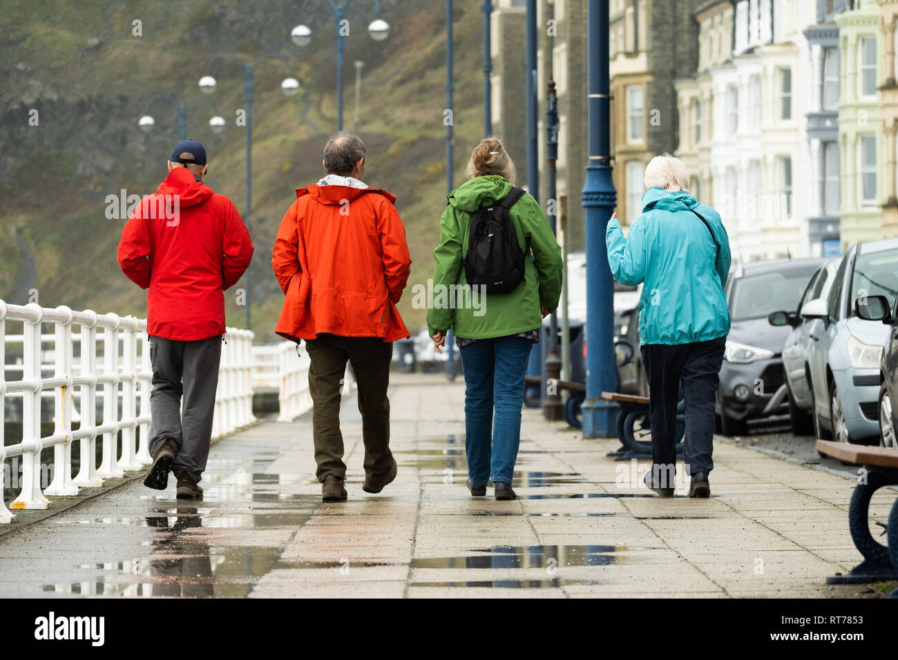 Aberystwyth Wales UK, giovedì 28 febbraio 2019. Meteo REGNO UNITO: l'ultimo giorno di inverno meteorologico, le persone nella loro pioggia-vestiti, passeggiata lungo il mare in Aberystwyth su un grigio, fredda e umida giornata, in netto contrasto con la recente record e il calore del sole e molto più tipiche di ventoso e condizioni dello scambiatore di calore per essere previsto per la fine di febbraio e inizio di marzo Photo credit: keith morris/Alamy Live News Foto Stock