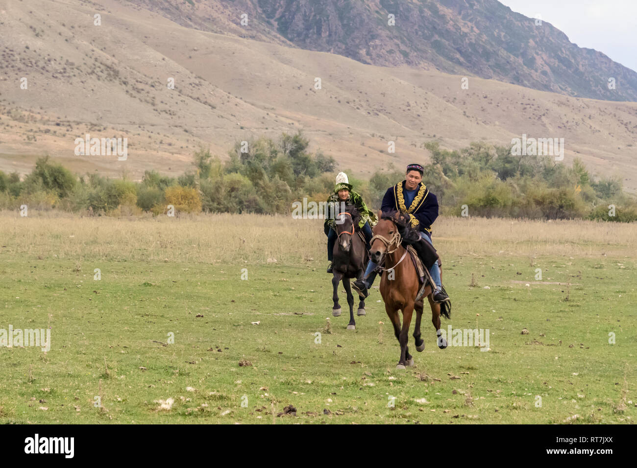 Coppia di giovani kazako racing i loro cavalli attraverso un piano erboso, Soggiornare, Kazakistan Foto Stock