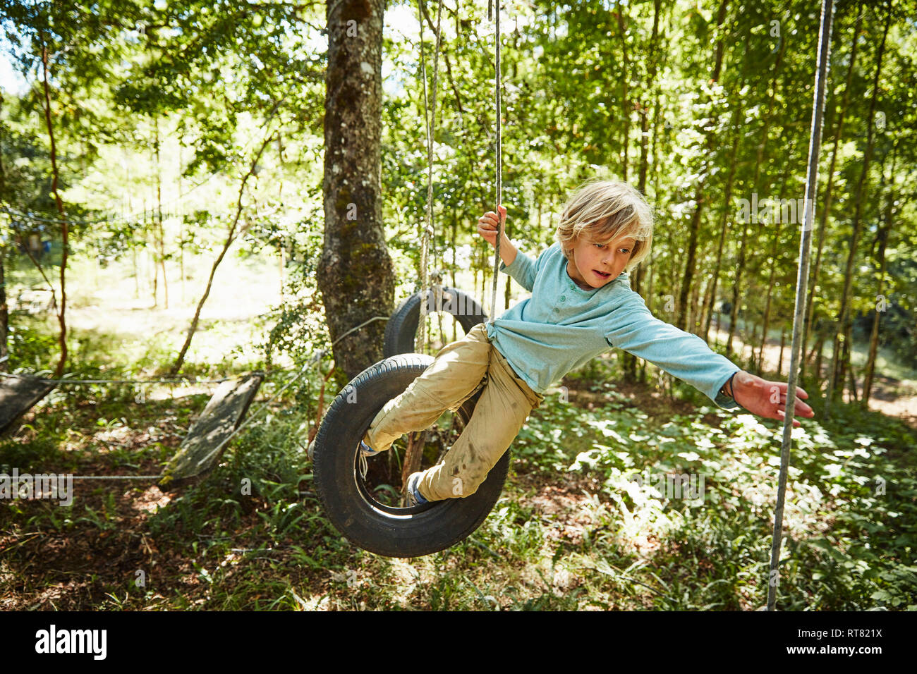 Bilanciamento del ragazzo su pneumatici a un parco avventura in foresta Foto Stock