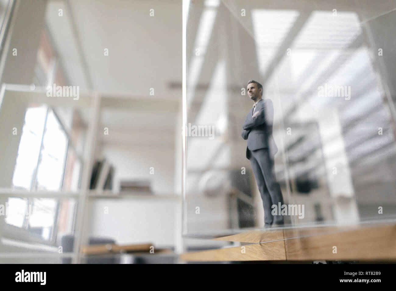 Imprenditore figurina in piedi in un ufficio moderno, guardando attraverso il pannello di vetro Foto Stock