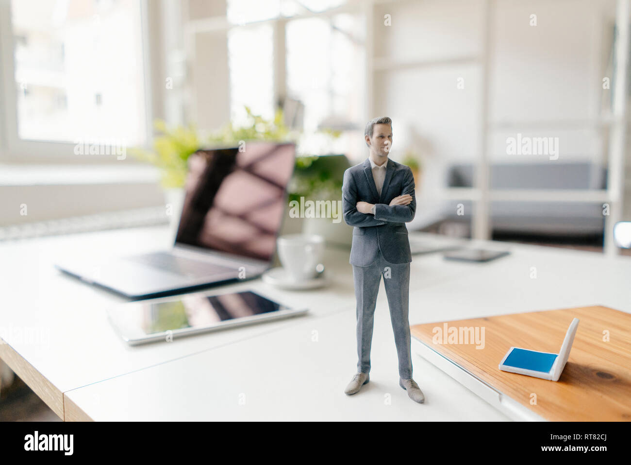 Imprenditore figurina in piedi su una scrivania con i dispositivi mobili Foto Stock