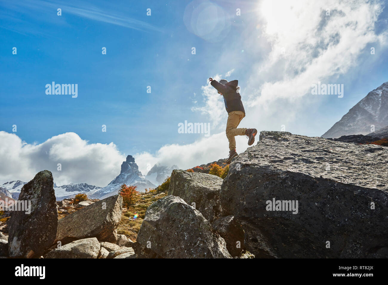 Il Cile, Cerro Castillo, ragazzo saltando dal rock in mountainscape Foto Stock