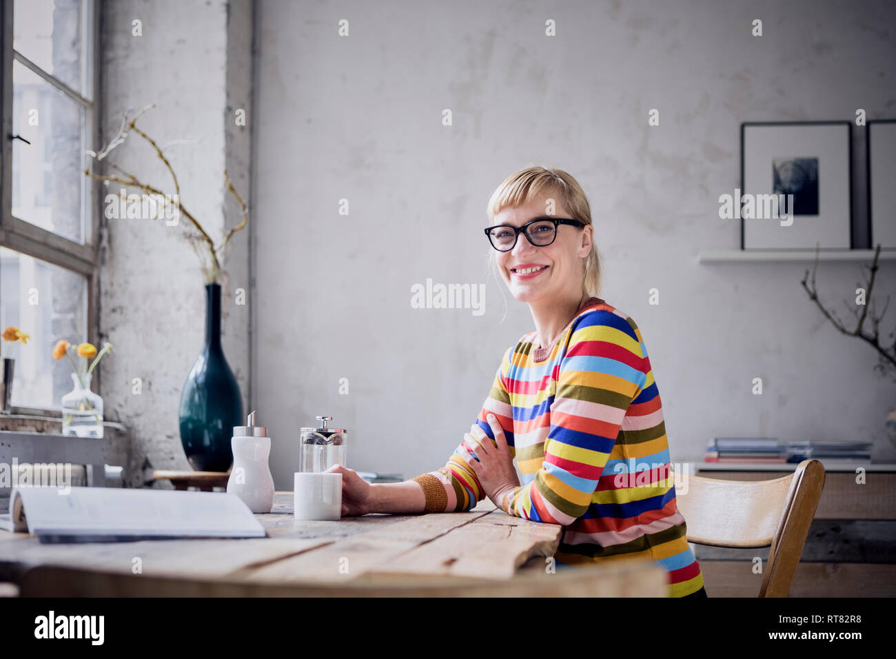 Ritratto di donna ridere con la tazza di caffè in un loft Foto Stock