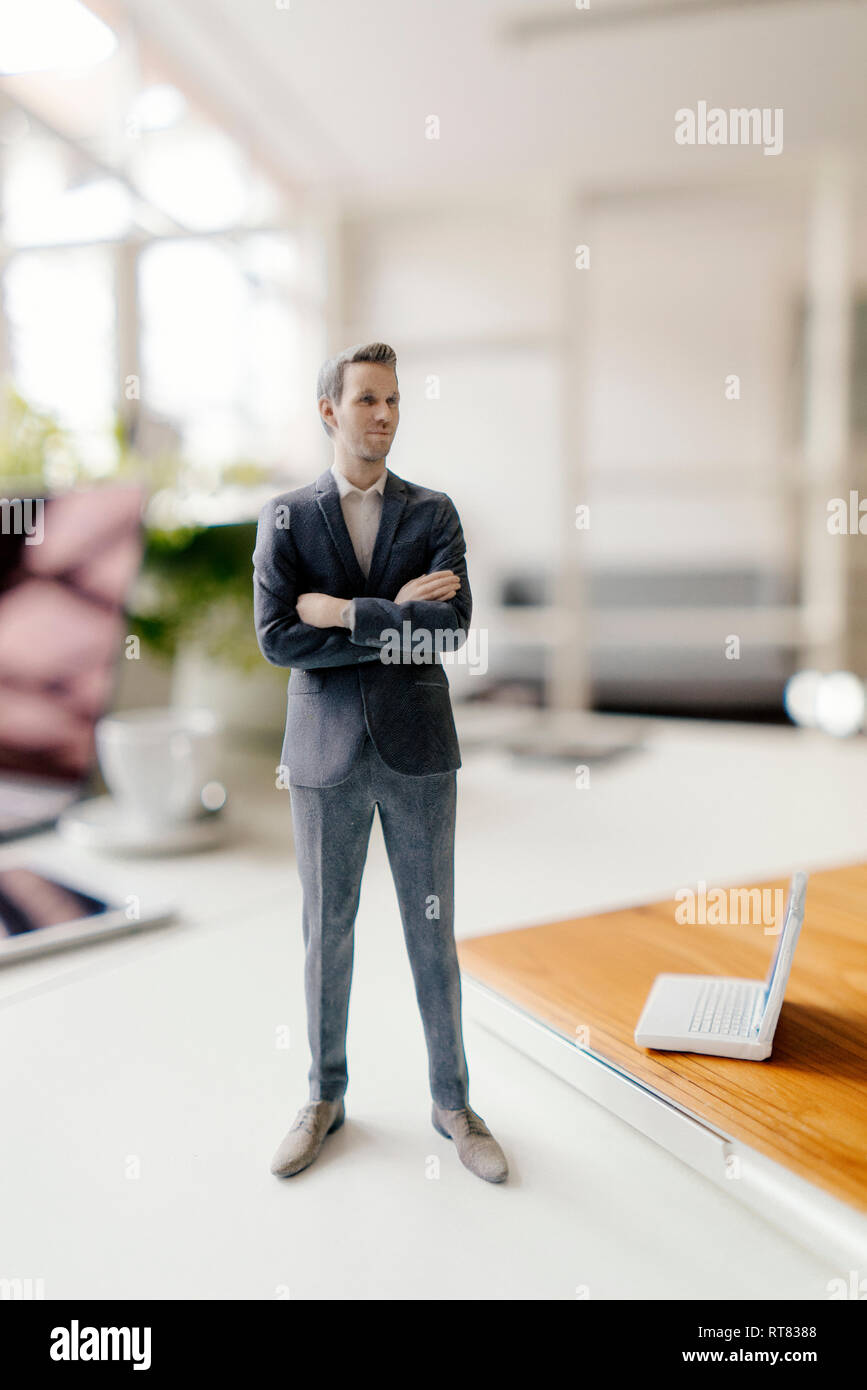 Imprenditore figurina in piedi su una scrivania con i dispositivi mobili Foto Stock