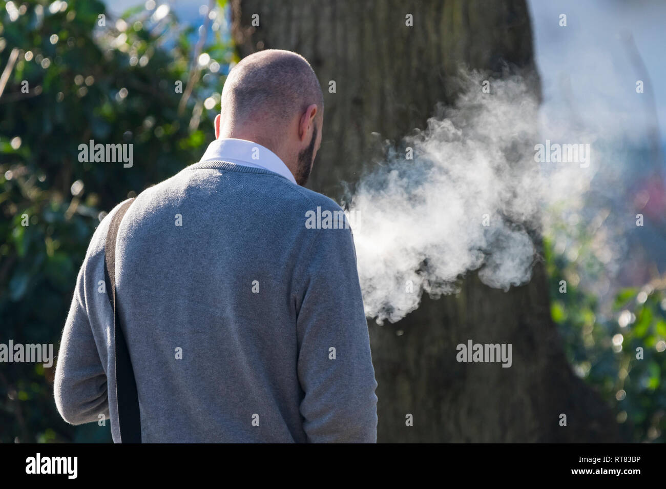 Uomo caucasico che cammina mentre vaping, emettendo grandi quantità di fumo, nel Regno Unito. Sigaretta elettronica. Foto Stock