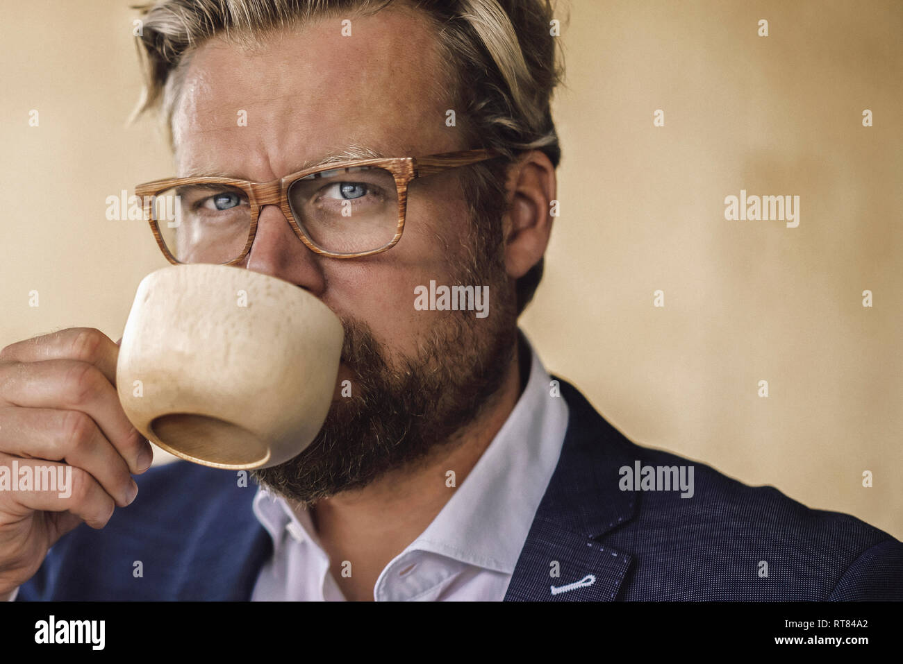 Imprenditore in piedi in ufficio, bere il caffè da una tazza di legno Foto Stock