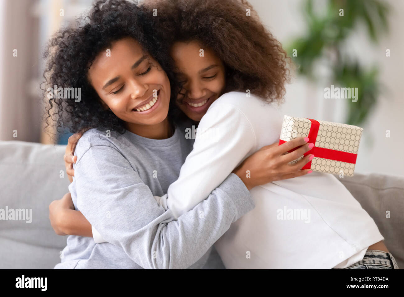 Figlia africana congratularmi con la madre con relativo compleanno persone abbracciando Foto Stock