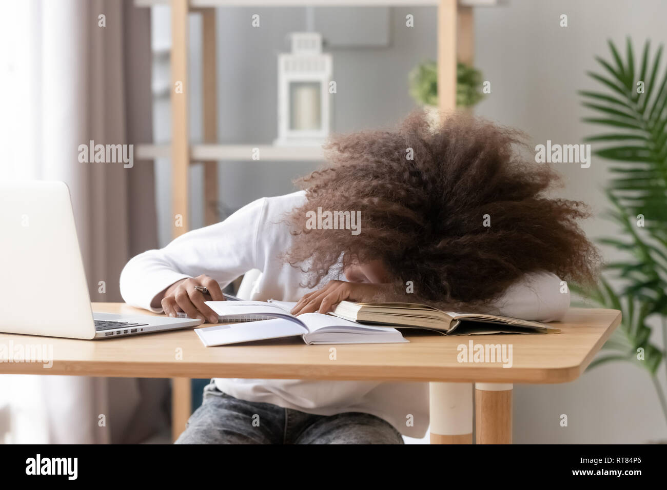 Schoolgirl dorme seduto alla scrivania in aula durante lo studio Foto Stock