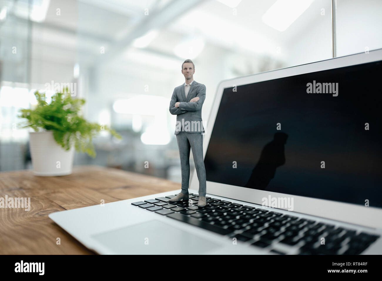 Imprenditore figurina in piedi sul computer portatile in ufficio moderno Foto Stock
