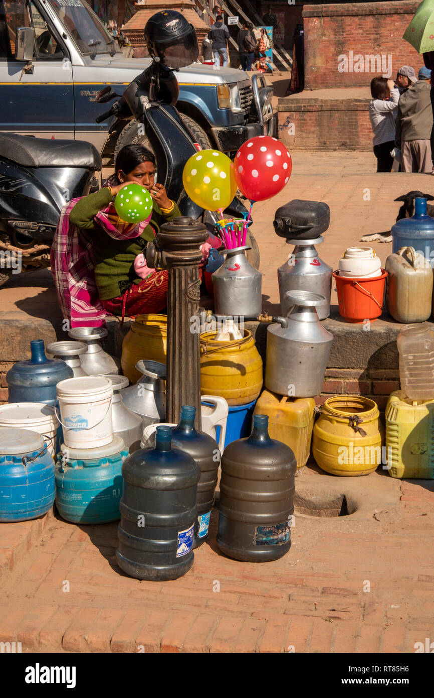 Il Nepal, Valle di Kathmandu, Bhaktapur, donna che soffia su palloncini a pubblico acqua di rubinetto di alimentazione Foto Stock