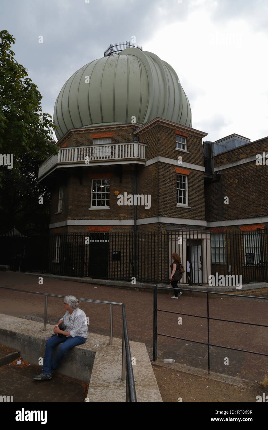 Una donna si siede da solo nelle vicinanze del grande storico edificio equatoriale con un telescopio cupola all'Osservatorio Reale di Greenwich a Londra, Regno Unito. Foto Stock