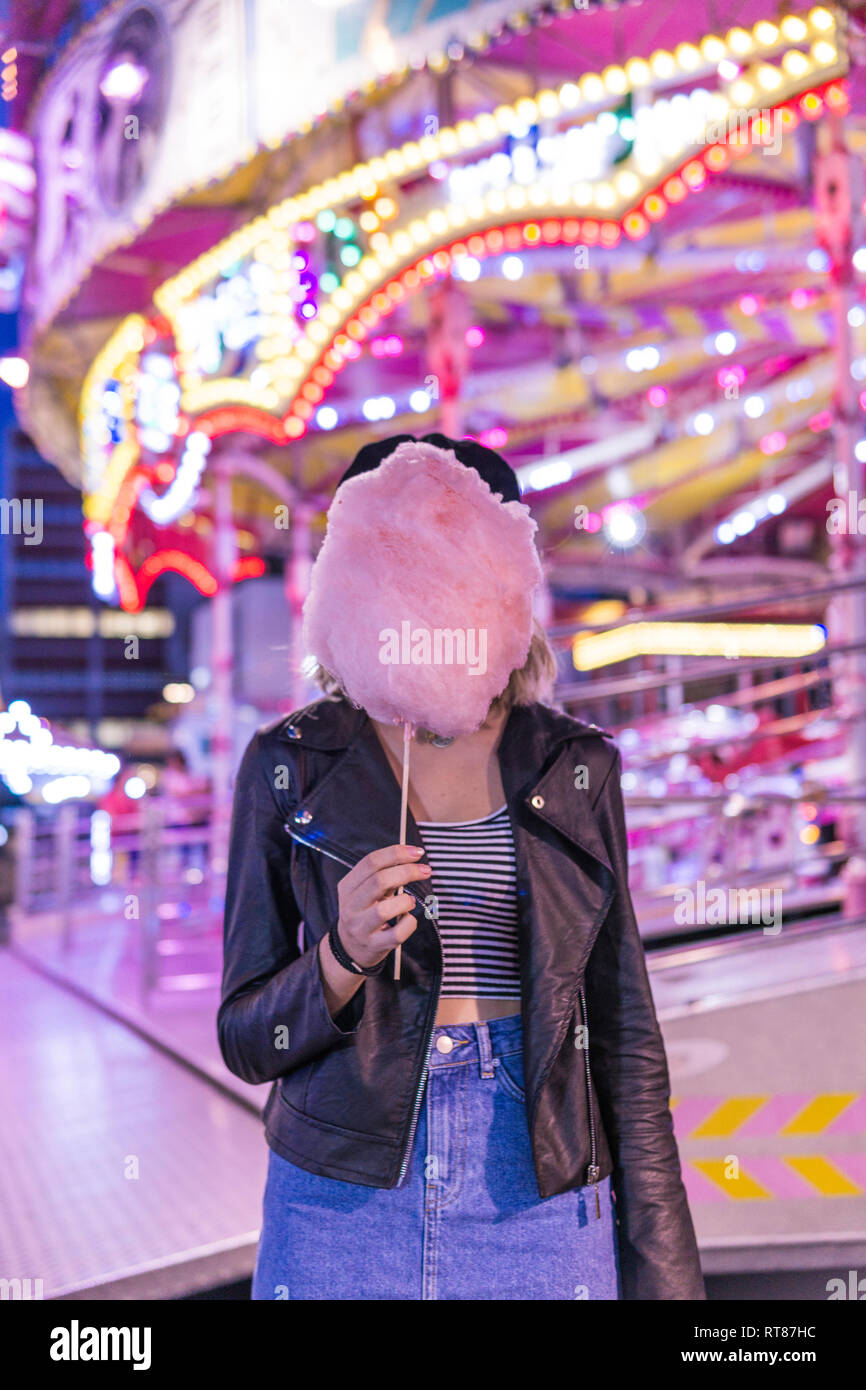Ragazza adolescente nasconde il suo volto dietro rosa zucchero filato al fair Foto Stock