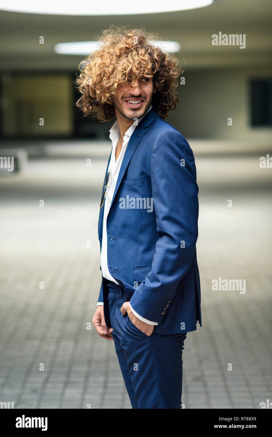 Ritratto di giovane imprenditore alla moda con capelli ricci indossare tuta blu Foto Stock