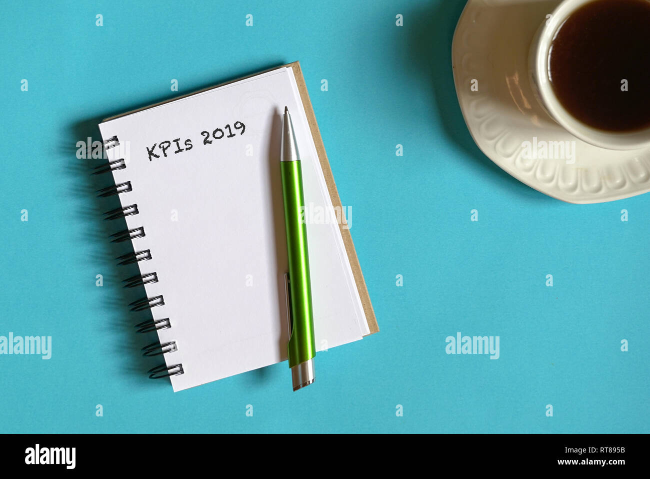 Vista elenco degli obiettivi con memo pad, una tazza di caffè e penna pastello su sfondo blu Foto Stock
