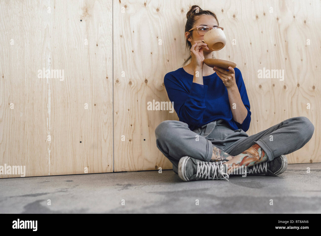 Giovane donna prendendo una pausa in ufficio, bere il caffè da una tazza di legno Foto Stock