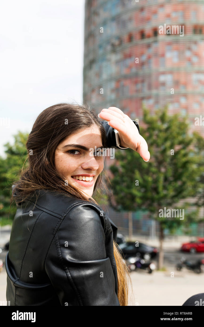 Spagna Barcellona, ritratto di sorridere giovane donna in città gli occhi di schermatura Foto Stock