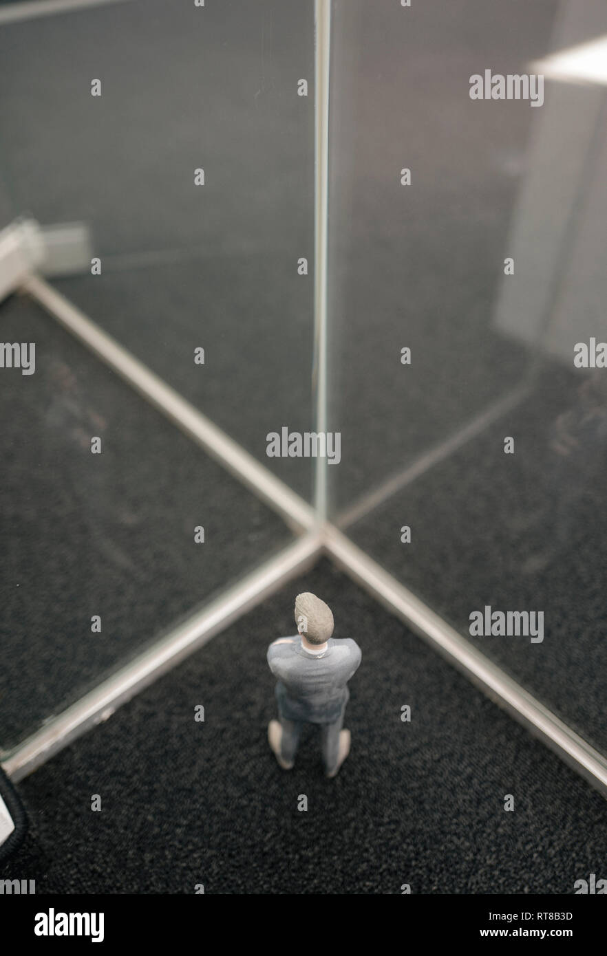Imprenditore figurina in piedi tra lastre di vetro Foto Stock