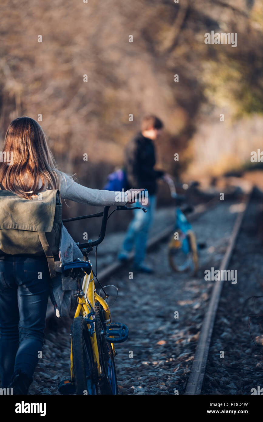 Un ragazzo e una ragazza camminare sul treno via con le biciclette Foto Stock