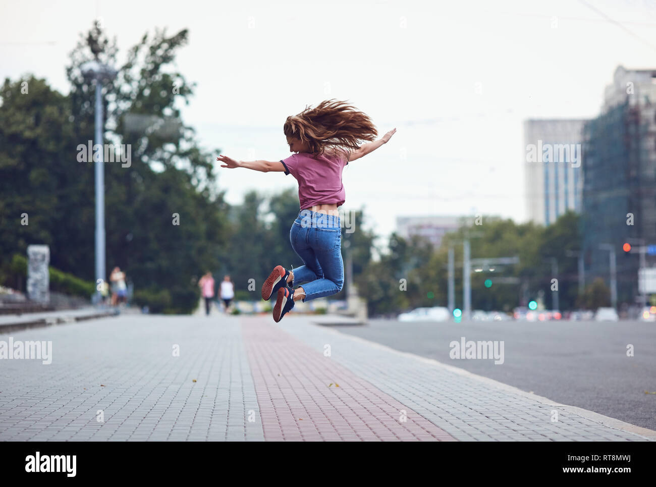 Happy girl jumping vista posteriore esterno Foto Stock
